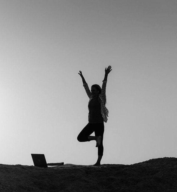 Silhouette of a person in a powerful yoga pose against a vibrant sunrise.