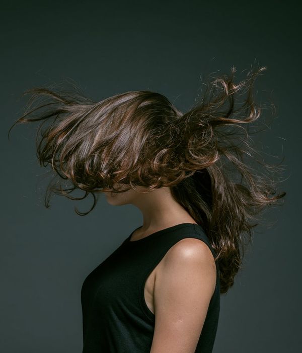 Woman in a dynamic yoga pose with flowing movements against a dark background.